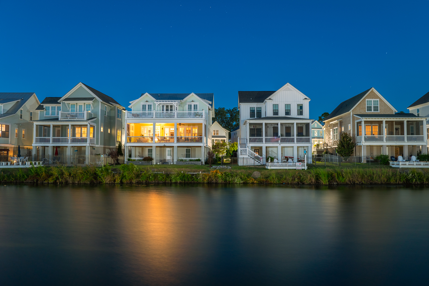 Lakeside houses illuminated at night.