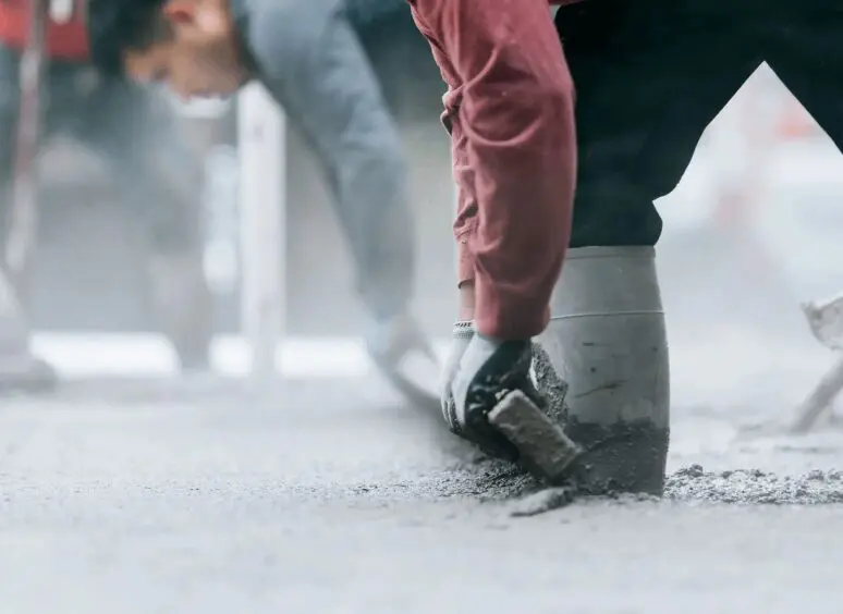 Worker leveling fresh concrete with trowel.