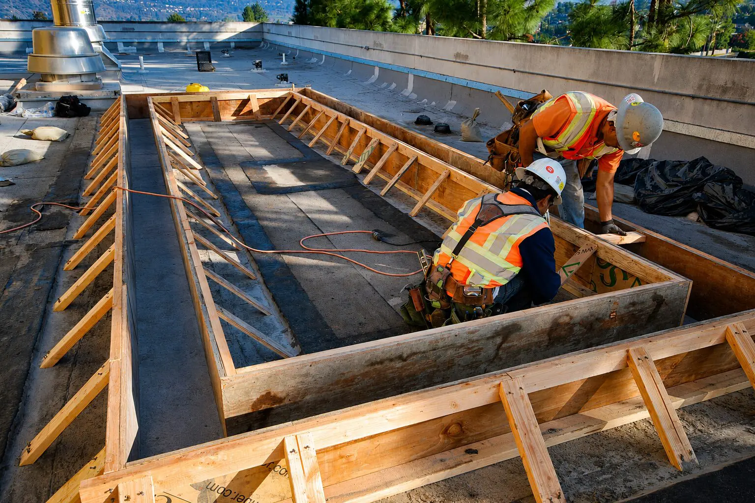 Workers assembling rooftop wooden framework.