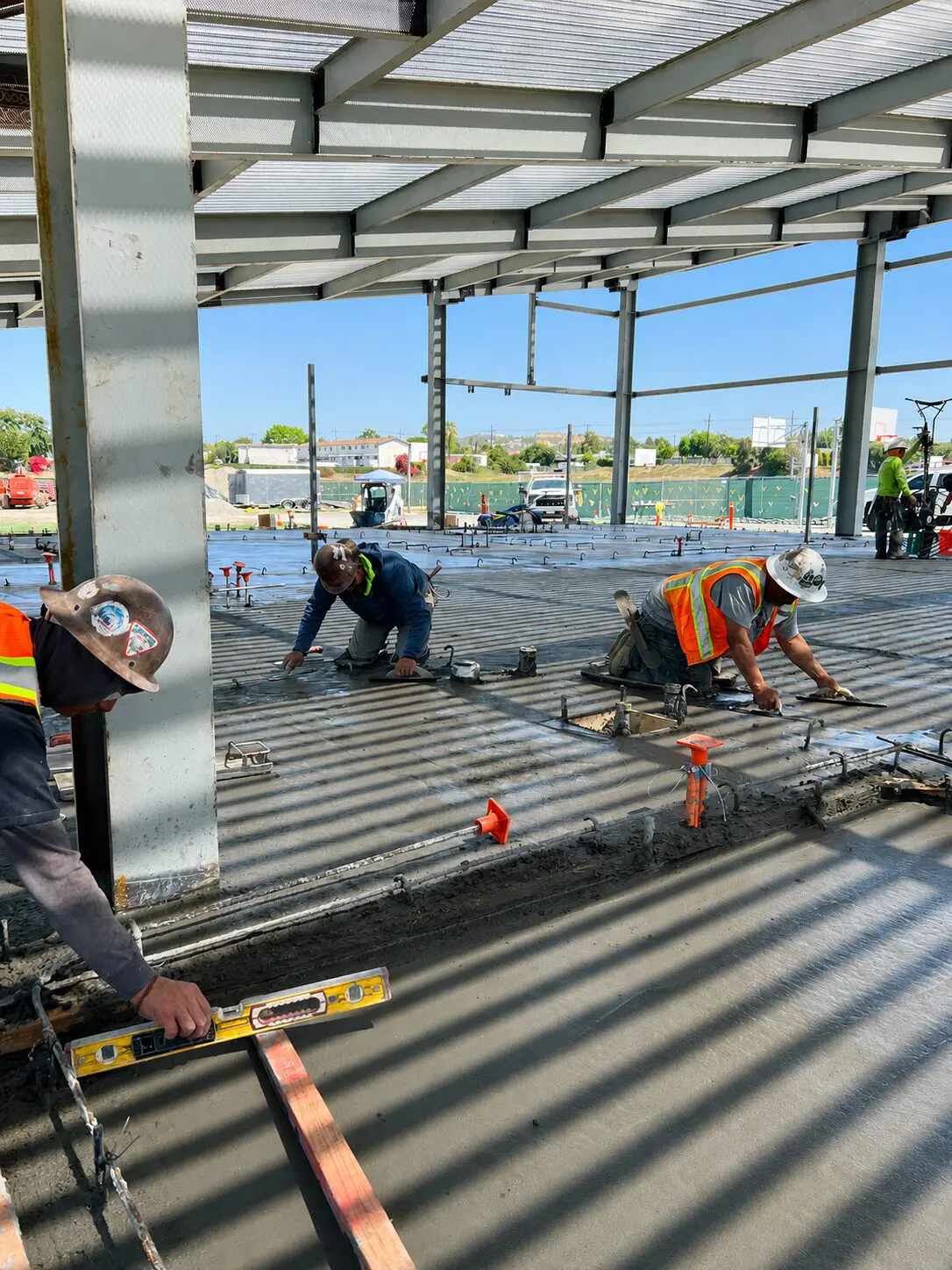 Construction workers leveling wet concrete floor.