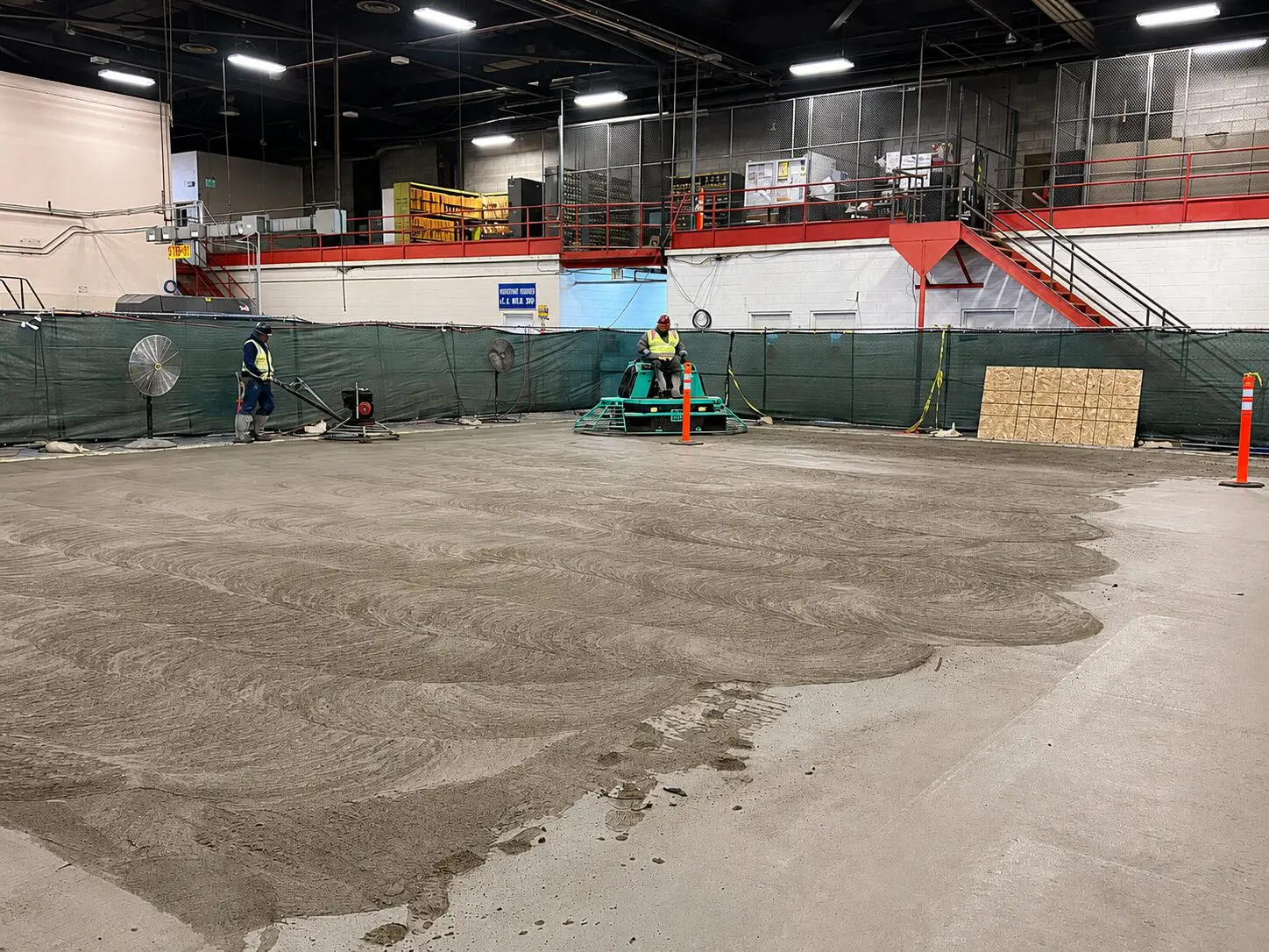 Construction workers smoothing concrete floor
