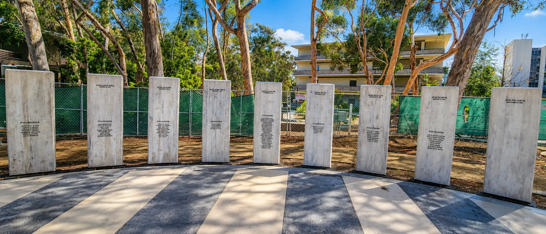 Commemorative columns surrounded by trees and building.